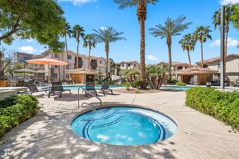 A pool surrounded by palm trees and lounge chairs.